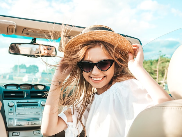Foto retrato de joven hermosa y sonriente mujer hipster en coche descapotable