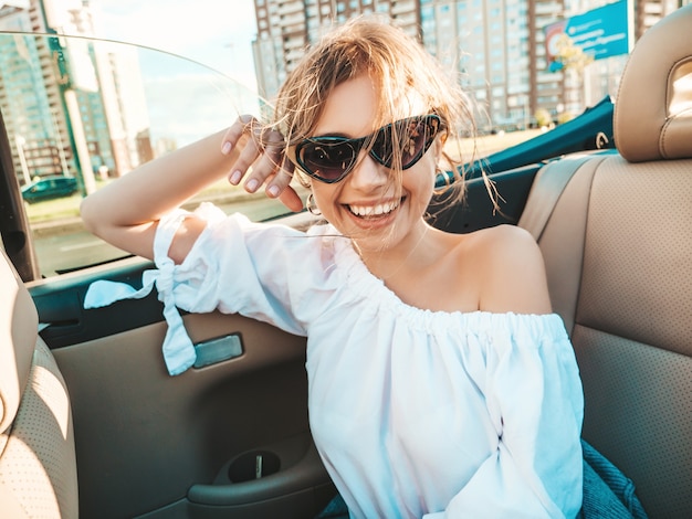 Retrato de joven hermosa y sonriente mujer hipster en coche descapotable