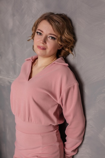 retrato de una joven hermosa con un vestido rosa de fondo gris