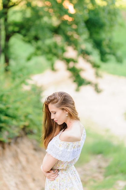 Retrato de una joven hermosa en un vestido de verano. Sesión de fotos de verano en el parque al atardecer. Fotografía de cerca.