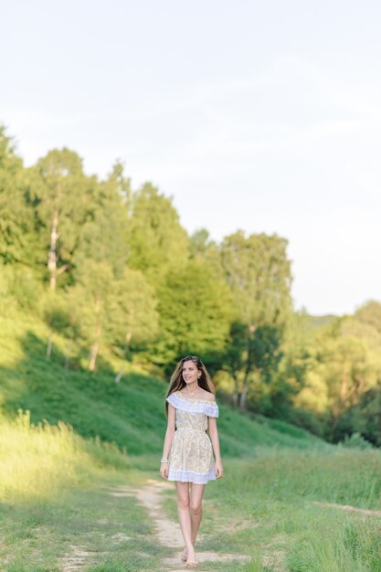 Retrato de una joven hermosa en un vestido de verano. Sesión de fotos de verano en el parque al atardecer.