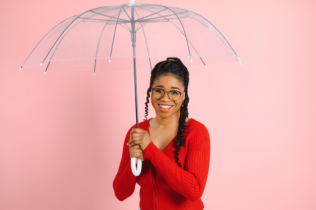 retrato, de, joven, hermoso, mujer americana africana, tenencia, paraguas, aislado, en, un, rosa, plano de fondo