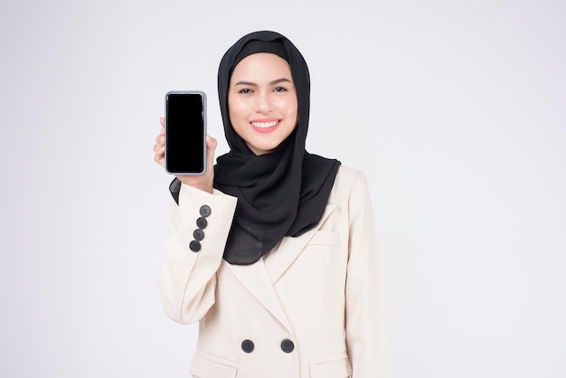 retrato, de, joven, hermoso, mujer musulmana, en, traje, utilizar, teléfono inteligente, encima, fondo blanco