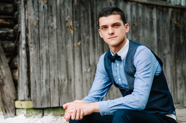 Retrato joven hermoso sentado junto a la pared de madera