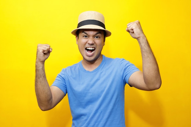 Retrato de un joven Hipster, un joven feliz, un vestido casual, una camiseta a rayas azules y un sombrero. Gesto de emoción, extiende los brazos tímidos y modestos en retratos de estudio con fondo de color amarillo