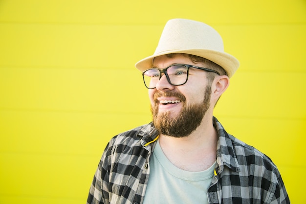 Retrato de un joven hipster positivo sonriendo sobre una pared amarilla tienda al aire libre fondo guapo t