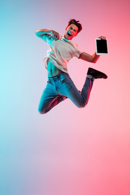 Retrato de joven hombre caucásico sobre fondo de estudio azul-rosa degradado en luz de neón