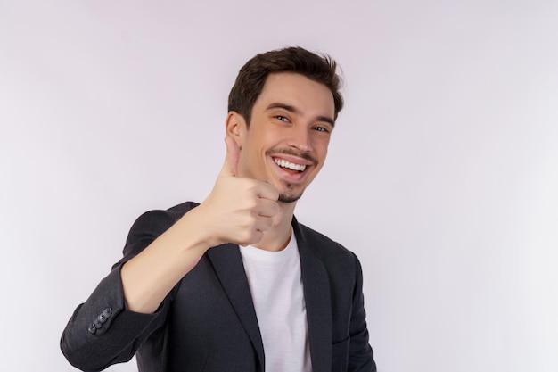 Foto retrato de un joven hombre de negocios feliz y sonriente que muestra un gesto de pulgar hacia arriba y mira la cámara aislada sobre fondo blanco