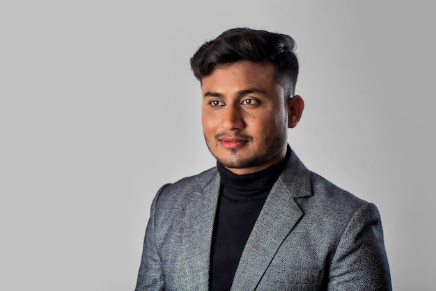 Retrato de un joven hombre de negocios indio feliz con una chaqueta de fondo gris posando satisfecho y exitoso hombre con traje formal