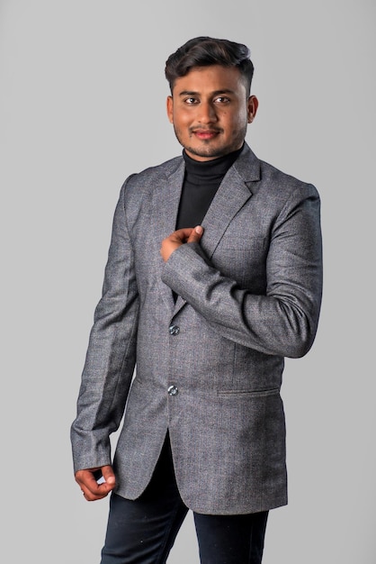 Retrato de un joven hombre de negocios indio feliz con una chaqueta de fondo gris posando satisfecho y exitoso hombre con traje formal