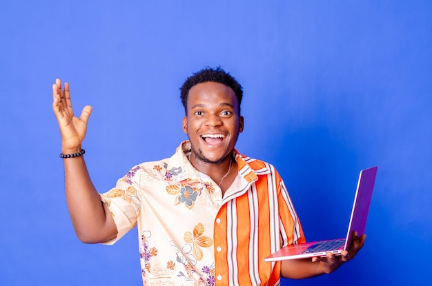 Retrato de un joven hombre de negocios moderno de pie sosteniendo una laptop y mirando a la cámara con una sonrisa feliz