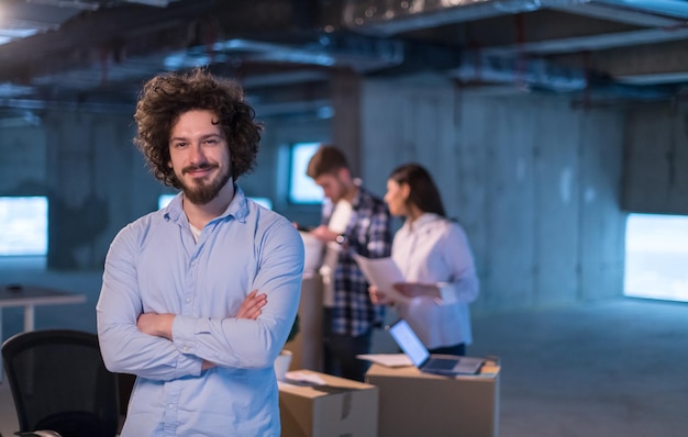 retrato de un joven hombre de negocios en el sitio de construcción revisando documentos y flujo de trabajo comercial con colegas en segundo plano en una nueva oficina de inicio