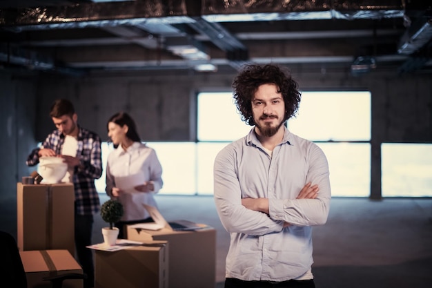 retrato de un joven hombre de negocios en el sitio de construcción revisando documentos y flujo de trabajo comercial con colegas en segundo plano en una nueva oficina de inicio