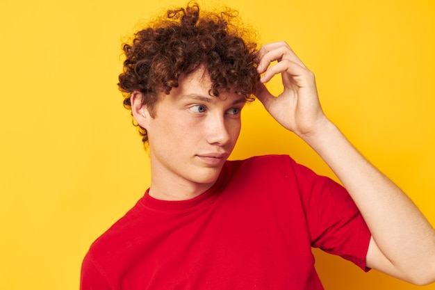 Retrato de un joven hombre rizado camiseta roja diversión posando ropa casual fondo aislado inalterado