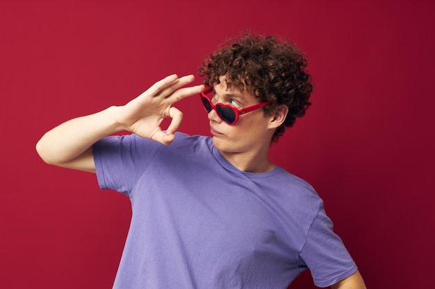 Retrato de un joven hombre rizado gestos con las manos gafas en forma de corazón posando fondo aislado