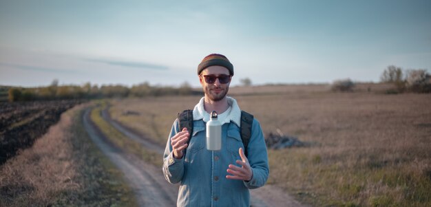 Retrato de joven inconformista seguro de sí mismo con botella ecológica de aluminio para agua