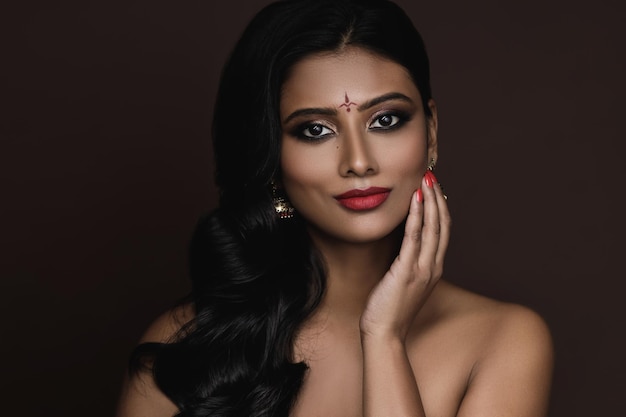 Retrato de joven india con hermoso maquillaje y peinado sobre fondo marrón