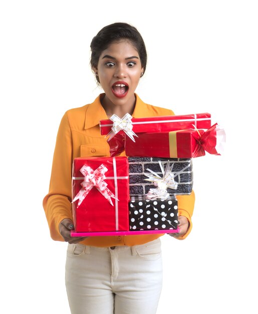 Retrato de joven India sonriente feliz sosteniendo cajas de regalo sobre un fondo blanco.