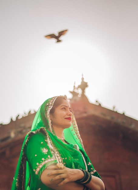 Retrato de una joven india sonriente de pie contra el cielo