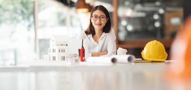 Retrato de una joven ingeniera sentada en su oficina sonriendo a la cámara