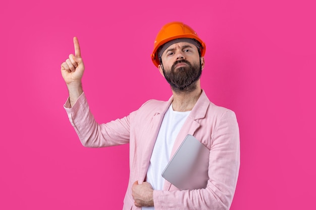 Retrato de un joven ingeniero de construcción que usa un sombrero duro naranja en una chaqueta rosa de pie sobre un fondo rojo de estudio Un hombre con una tableta en las manos