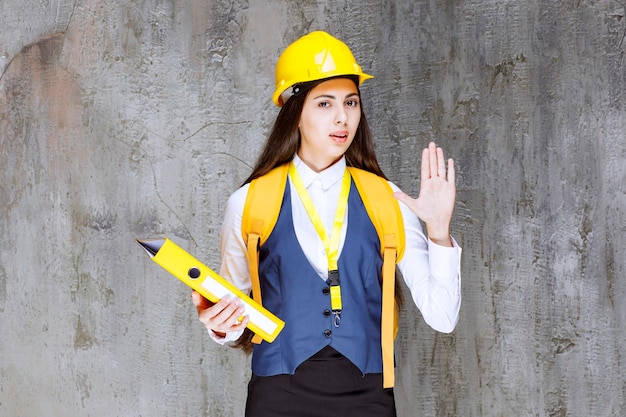 Retrato de joven ingeniero en hardhat mostrando señal de stop. foto de alta calidad