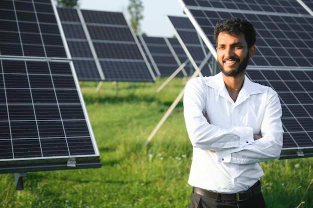 Retrato de un joven ingeniero indio de pie cerca de paneles solares con un claro fondo de cielo azul Habilidades de energía renovable y limpia en la India