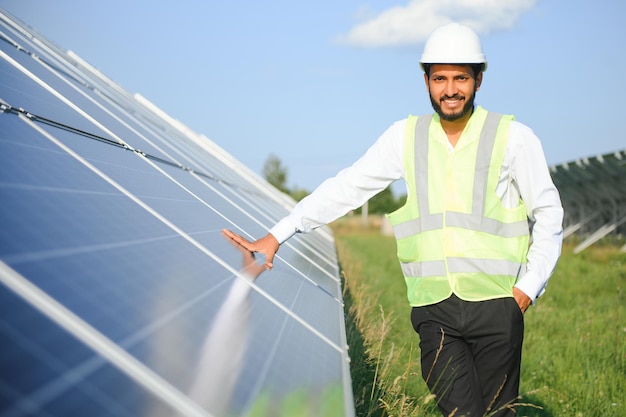 Retrato de un joven ingeniero indio de pie cerca de paneles solares con un claro fondo de cielo azul Habilidades de energía renovable y limpia en la India