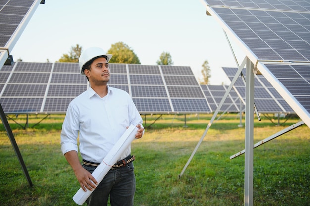 Retrato de un joven ingeniero o arquitecto indio en una granja de paneles solares El concepto de energía limpia