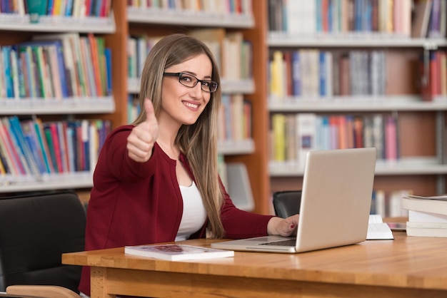 retrato, de, un, joven, inteligente, estudiante, actuación, pulgares arriba, en, colegio, biblioteca, poca profundidad de campo