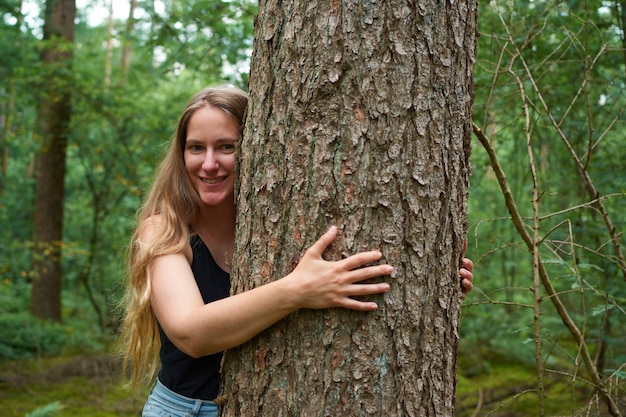 Un retrato de una joven italiana abrazando un árbol en un bosque