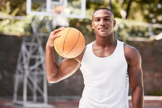 Retrato de un joven jugador de baloncesto masculino negro sosteniendo una pelota jugando un partido en una cancha de deportes local afuera Un hombre musculoso con actitud tomando un descanso para jugar un divertido juego recreativo