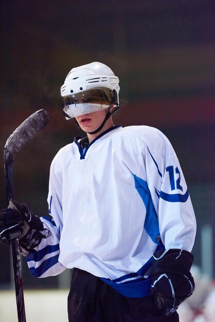 Retrato de joven jugador de hockey sobre hielo en formación en fondo negro