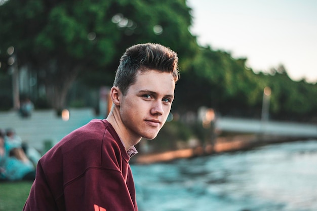 Retrato de un joven junto al lago contra los árboles