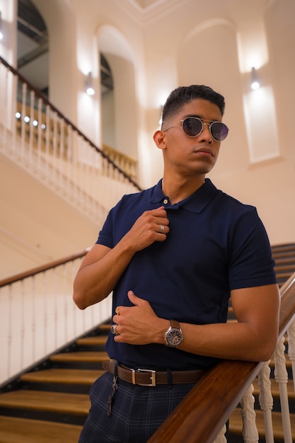 Retrato de un joven latino en un hermoso edificio antiguo. Polo azul y pantalón a cuadros