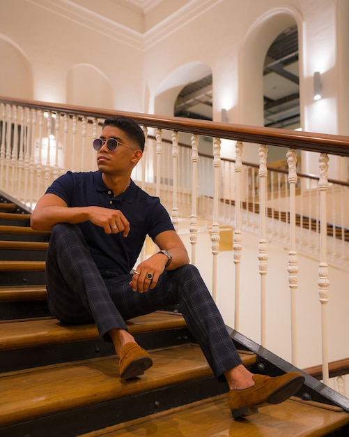 Retrato de un joven latino en un hermoso edificio antiguo. Polo azul y pantalón a cuadros