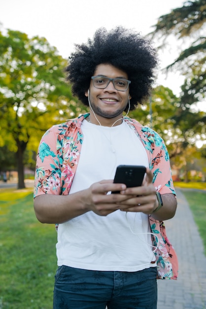 Retrato de joven latino usando su teléfono móvil mientras está de pie al aire libre en la calle