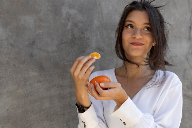 Retrato de una joven latinoamericana de 24 años comiendo una sabrosa mandarina Concepto de comida saludable