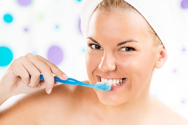 Foto retrato de una joven linda cepillándose los dientes en el baño.