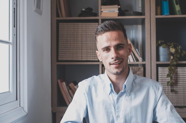 Foto retrato de un joven macho alegre sonriente divirtiéndose en casa joven caucásico atractivo estudiando independiente mirando a la cámara y posando para la foto xa