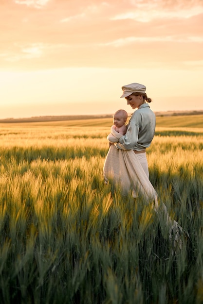 Un retrato de una joven madre con un bebé en sus brazos al atardecer en el concepto de familia feliz de campo