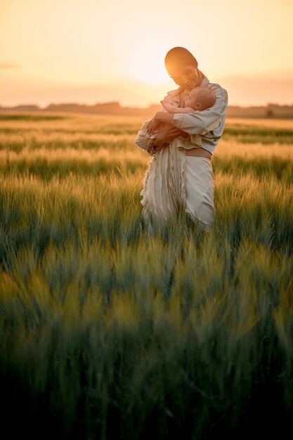 Un retrato de una joven madre con un bebé en sus brazos al atardecer en el concepto de familia feliz de campo