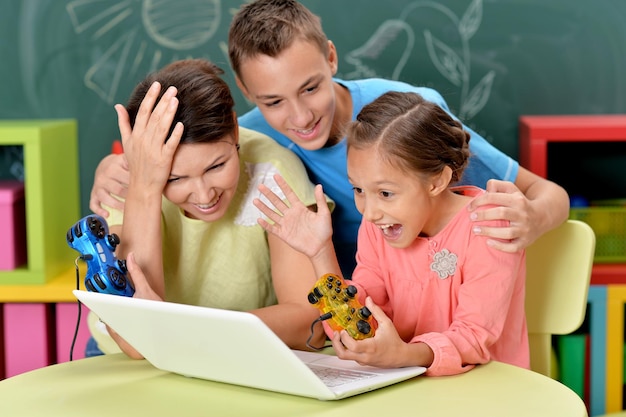 Retrato de joven madre con niños jugando ingenio juego de computadora