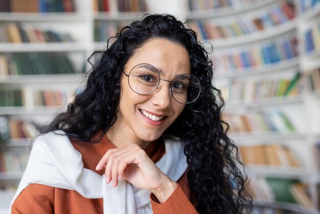 Retrato de una joven maestra india feliz sentada en el aula de la escuela sonriendo y mirando