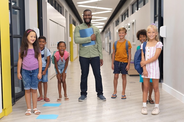 Retrato de un joven maestro afroamericano alegre con estudiantes primarios multirraciales