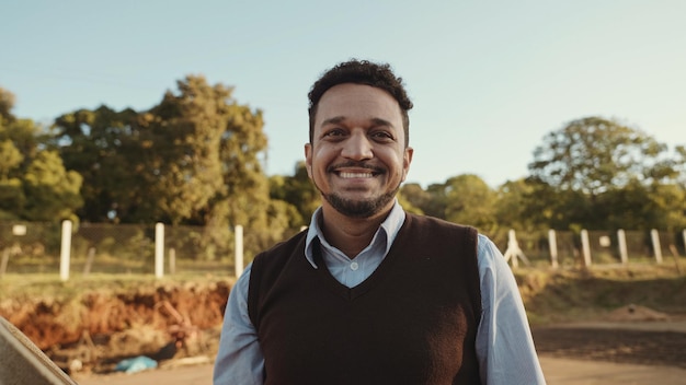 Retrato de un joven con las manos cruzadas en la camisa informal en la granja en el colorido fondo del cielo