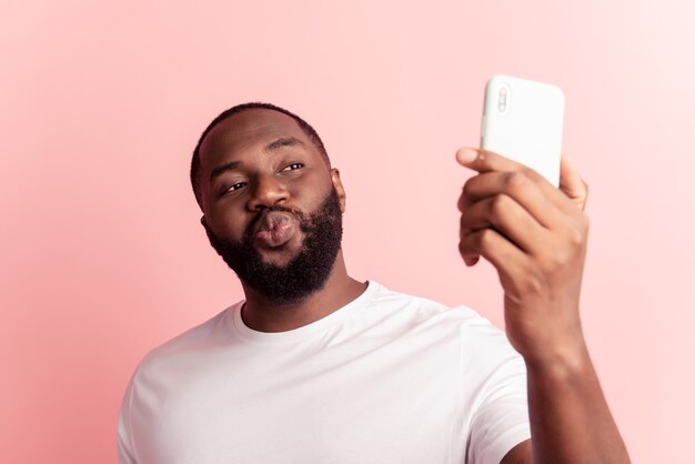 Retrato de joven mantenga la pantalla de aspecto divertido del teléfono inteligente