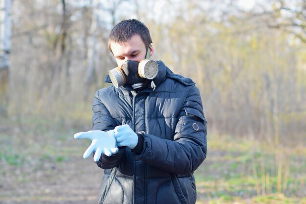 Foto retrato de joven con máscara de gas protectora usa guantes desechables de goma