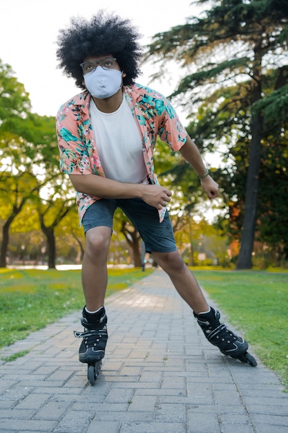 Retrato de joven con mascarilla mientras patina al aire libre en la calle