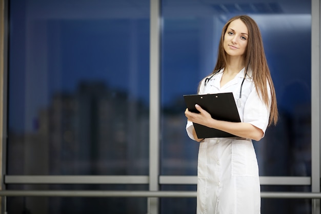 Retrato de un joven médico con una bata blanca de pie en el hospital